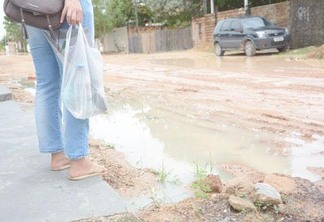 Moradora do bairro Centenário sai de casa de havaianas para não sujar os sapatos que usa para trabalhar (Foto: Rodrigo Otávio)