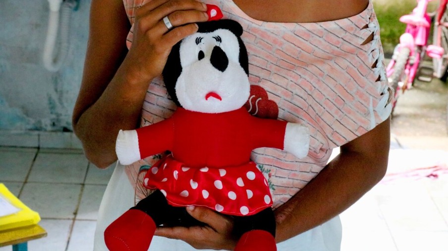 Mãe segurando o brinquedo favorito da filha (Foto: Wenderson Cabral/FolhaBV)