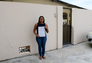 Nayra Barbosa de Souza exibe a escritura pública da casa onde vive desde criança, no Paraviana (Foto: Wenderson Cabral/FolhaBV)