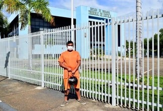 O sociólogo Ricardo Rodrigues, de 33 anos, está acorrentado a uma bola de ferro, vestido como presidiário, em frente ao TJRR (Foto: Nilzete Franco/FolhaBV)