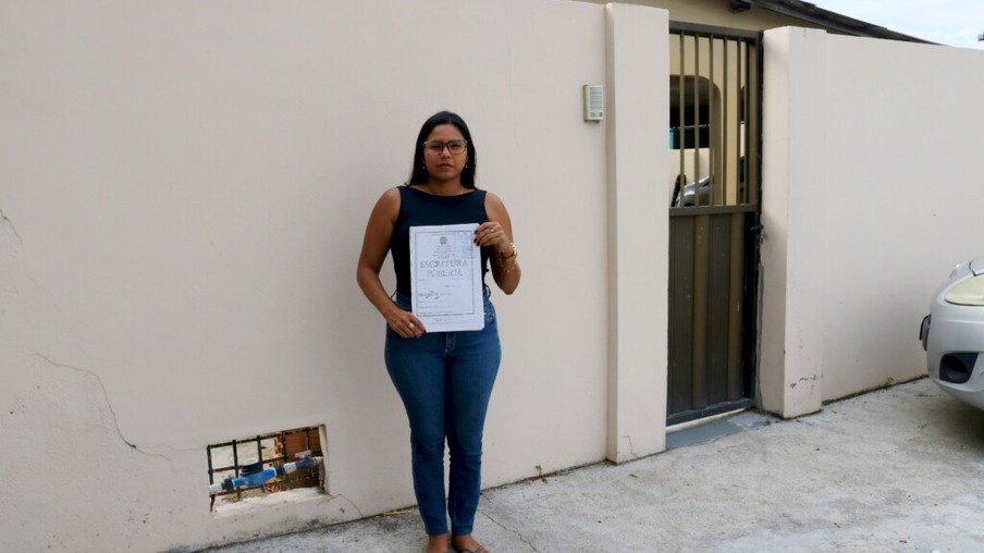 Nayra Barbosa de Souza exibe a escritura pública da casa onde vive desde criança, no Paraviana (Foto: Wenderson Cabral/FolhaBV)