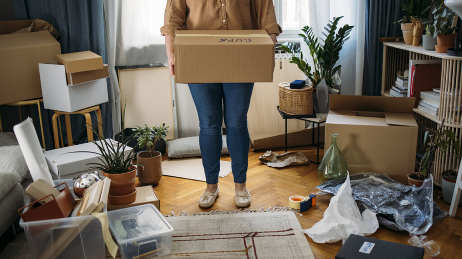 Young unrecognizable plus size woman moving out, carrying out boxes with personal belongings